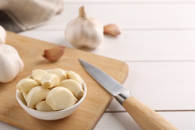 Photo of Fresh garlic and knife on white wooden table, closeup. Space for text