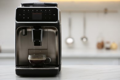 Photo of Modern electric espresso machine making coffee on white marble countertop in kitchen