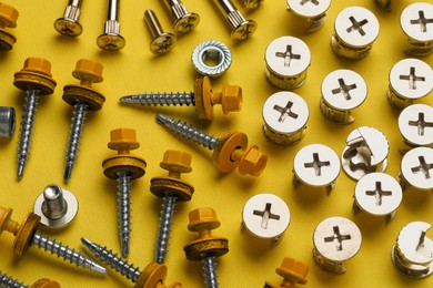 Photo of Many different fasteners on yellow background, above view