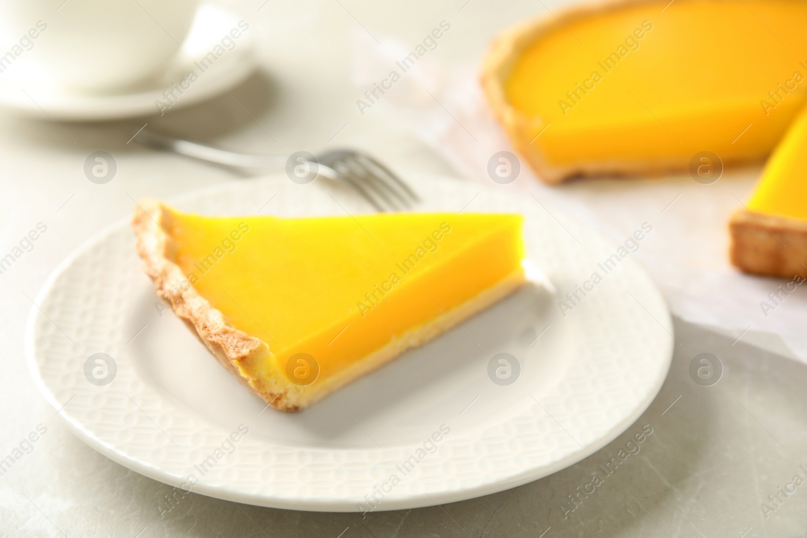 Photo of Slice of delicious homemade lemon pie on light grey table