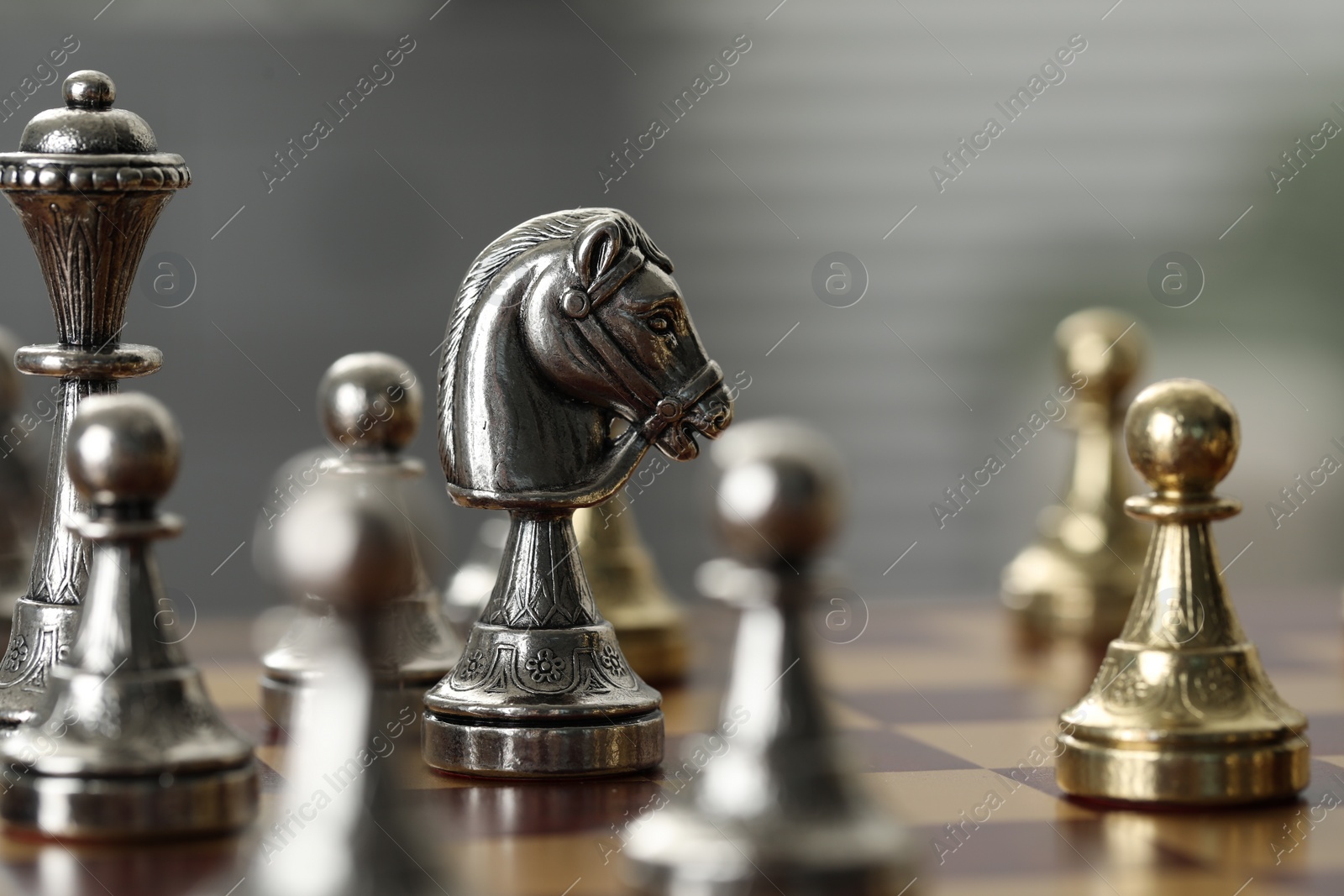 Photo of Silver knight and other chess pieces on game board, closeup
