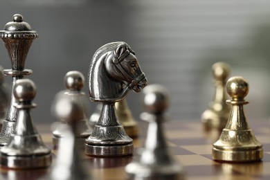 Photo of Silver knight and other chess pieces on game board, closeup