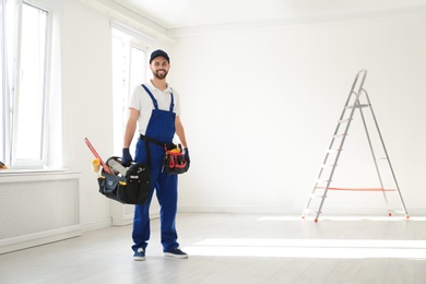 Full length portrait of construction worker with tools indoors, space for text