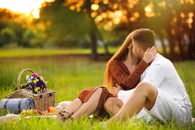Happy young couple kissing in park. Picnic season