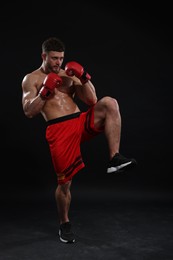 Man in boxing gloves fighting on black background