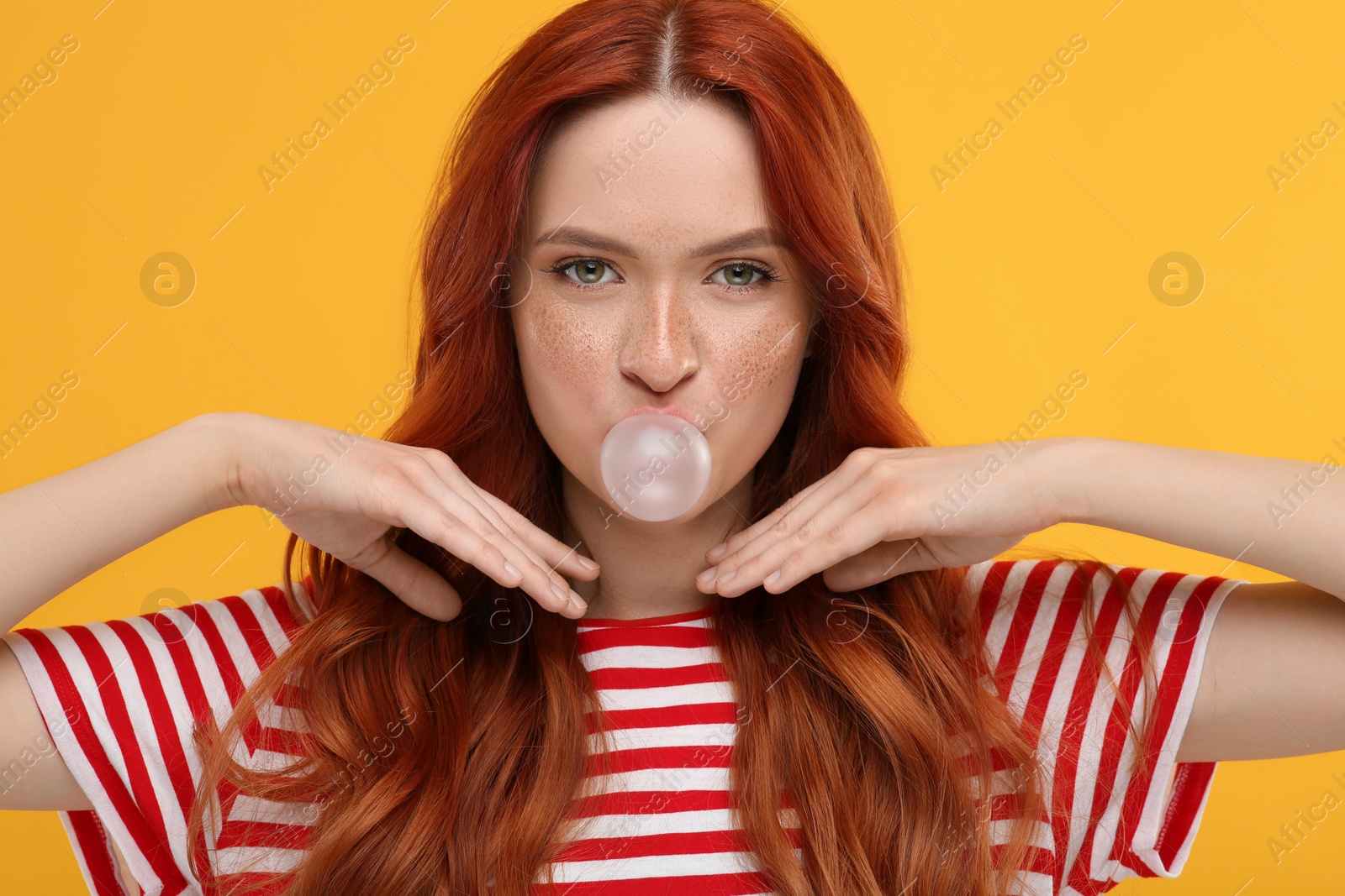 Photo of Portrait of beautiful woman blowing bubble gum on orange background