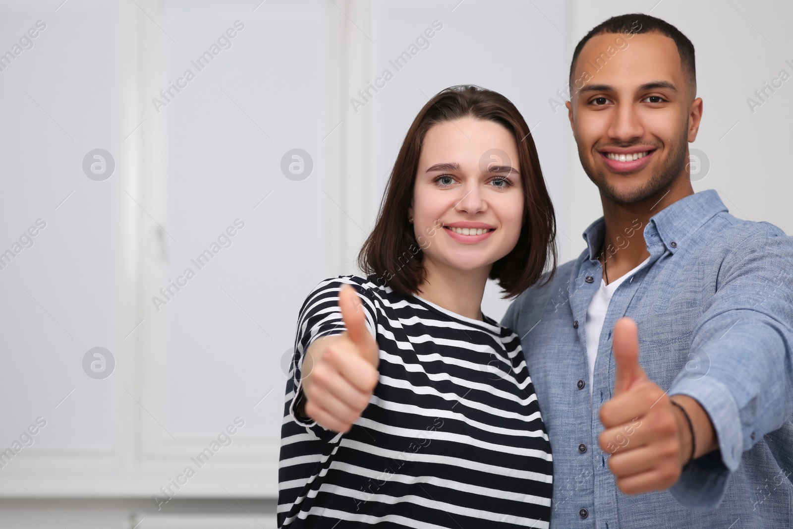 Photo of Dating agency. Happy couple showing thumbs up near white wall, space for text
