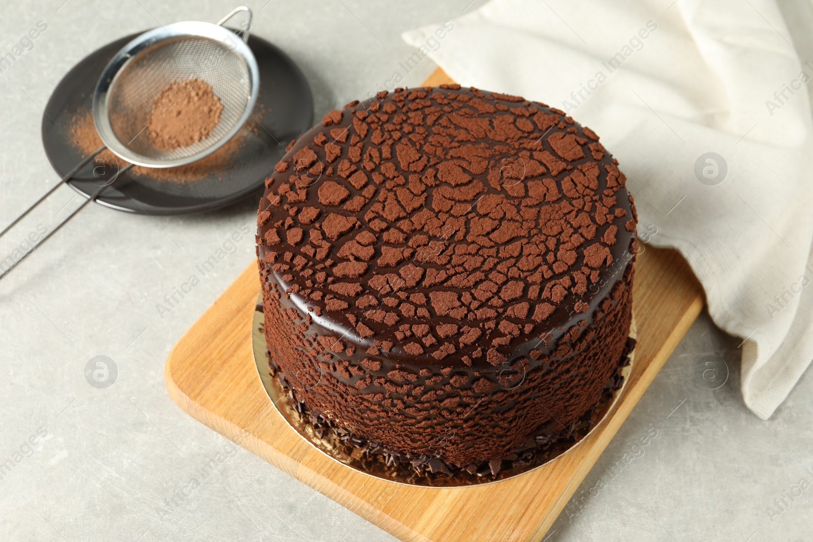 Photo of Delicious chocolate truffle cake and cocoa powder on light grey table