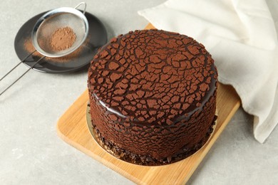 Delicious chocolate truffle cake and cocoa powder on light grey table