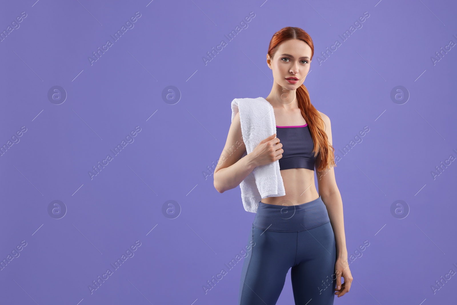 Photo of Woman in sportswear with towel on violet background, space for text