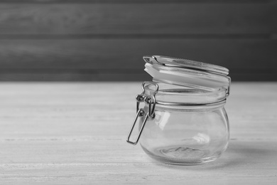 Empty glass jar on white wooden table, space for text