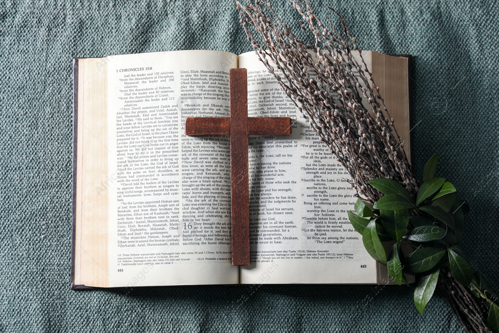Photo of Bible, wooden cross and bouquet with willow branches on color cloth, flat lay