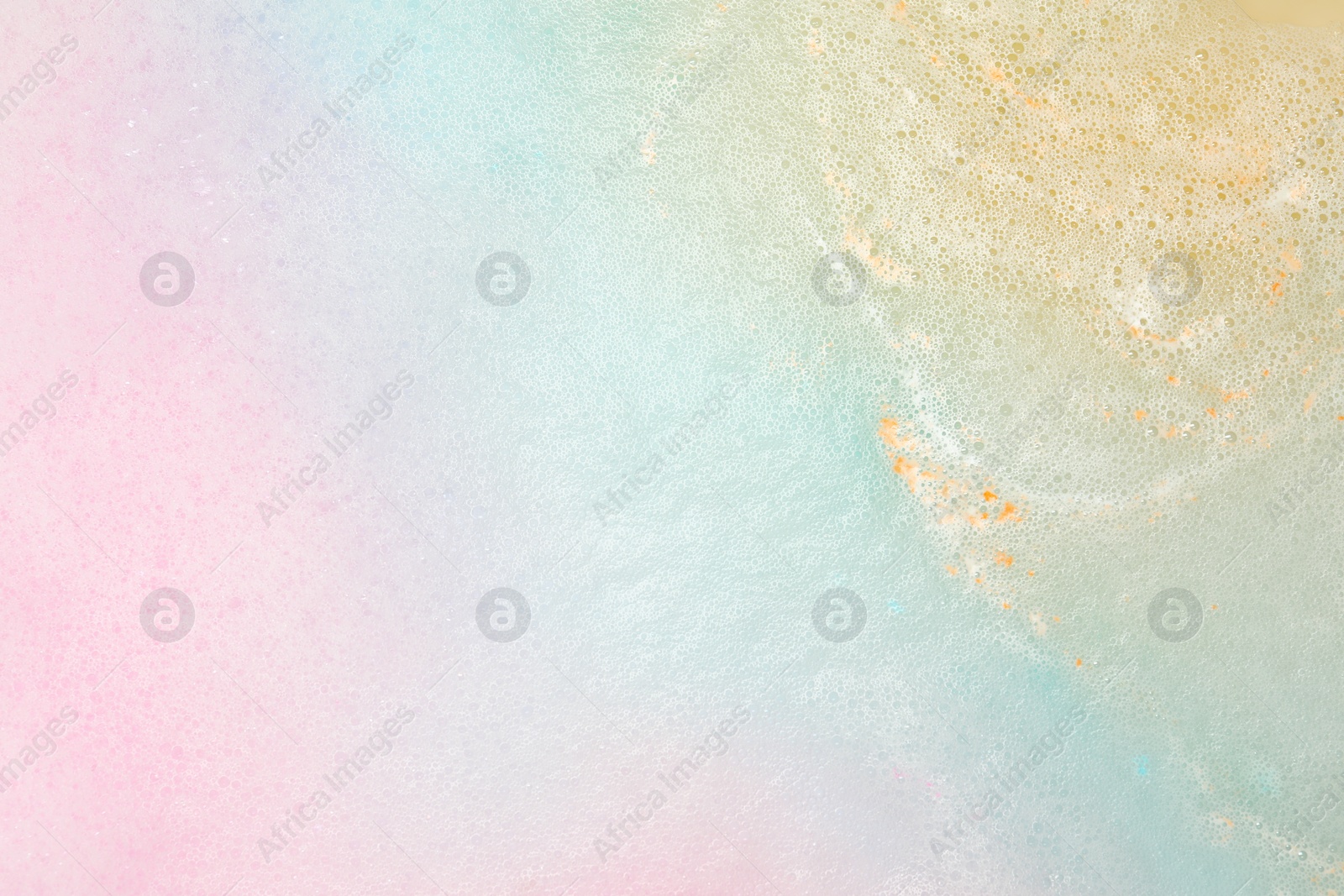 Photo of Colorful foam after dissolving bath bomb in water, closeup