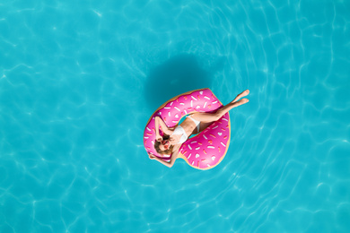Image of Young happy woman with inflatable ring in swimming pool, top view. Summer vacation