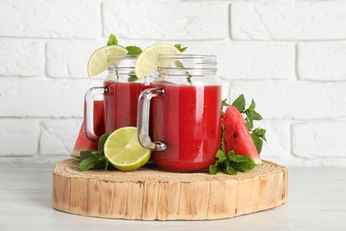 Photo of Tasty summer watermelon drink, limes and mint on white wooden table