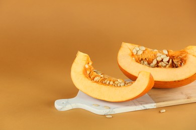 Photo of Cut fresh ripe pumpkin on orange background, space for text