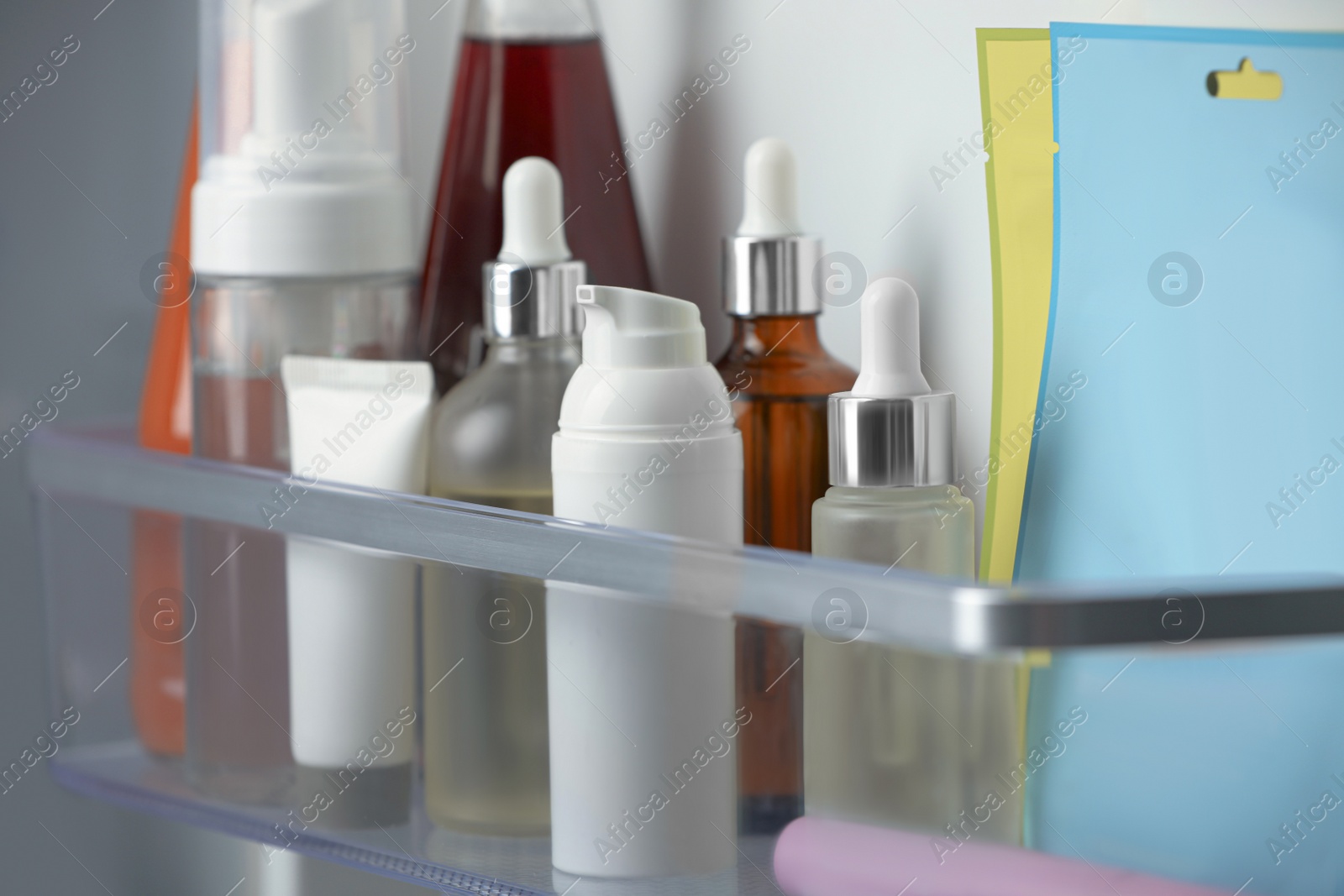 Photo of Different cosmetic products on shelf in refrigerator