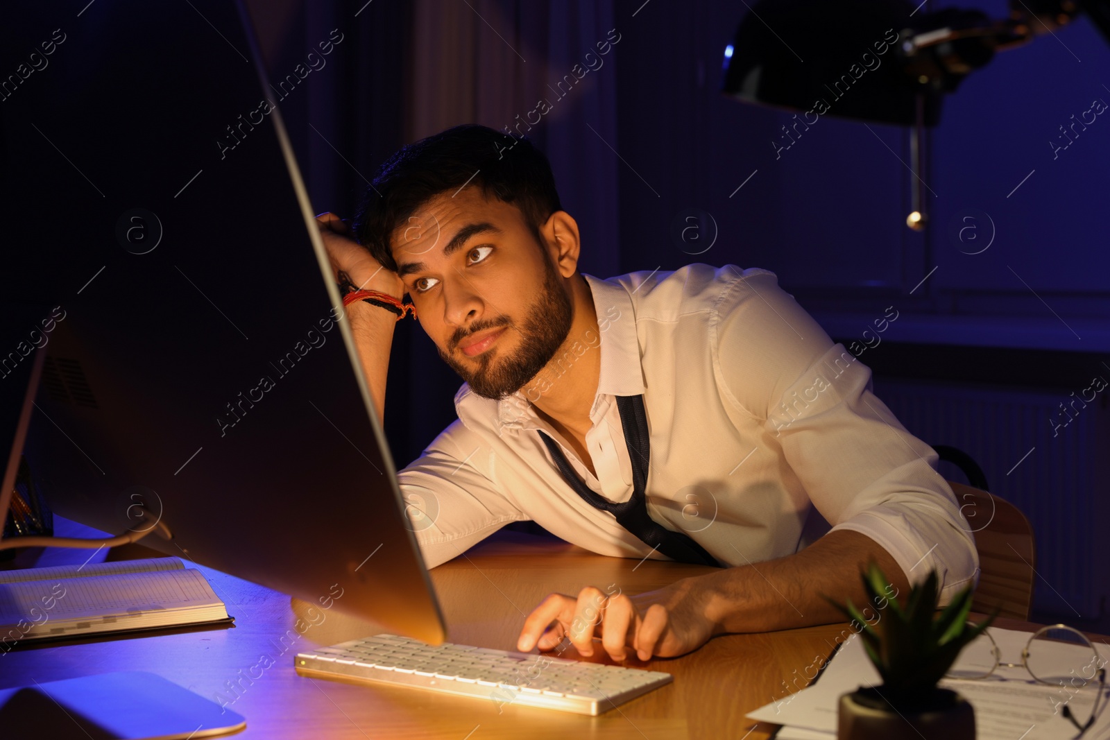 Photo of Tired young man working late in office