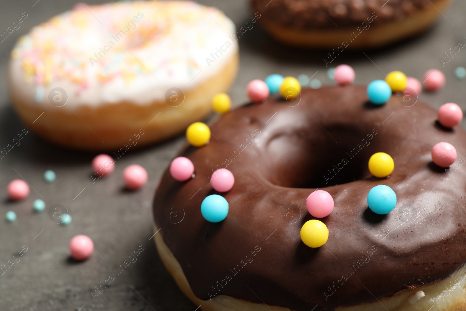 Photo of Yummy donut with colorful sprinkles on dark table, closeup
