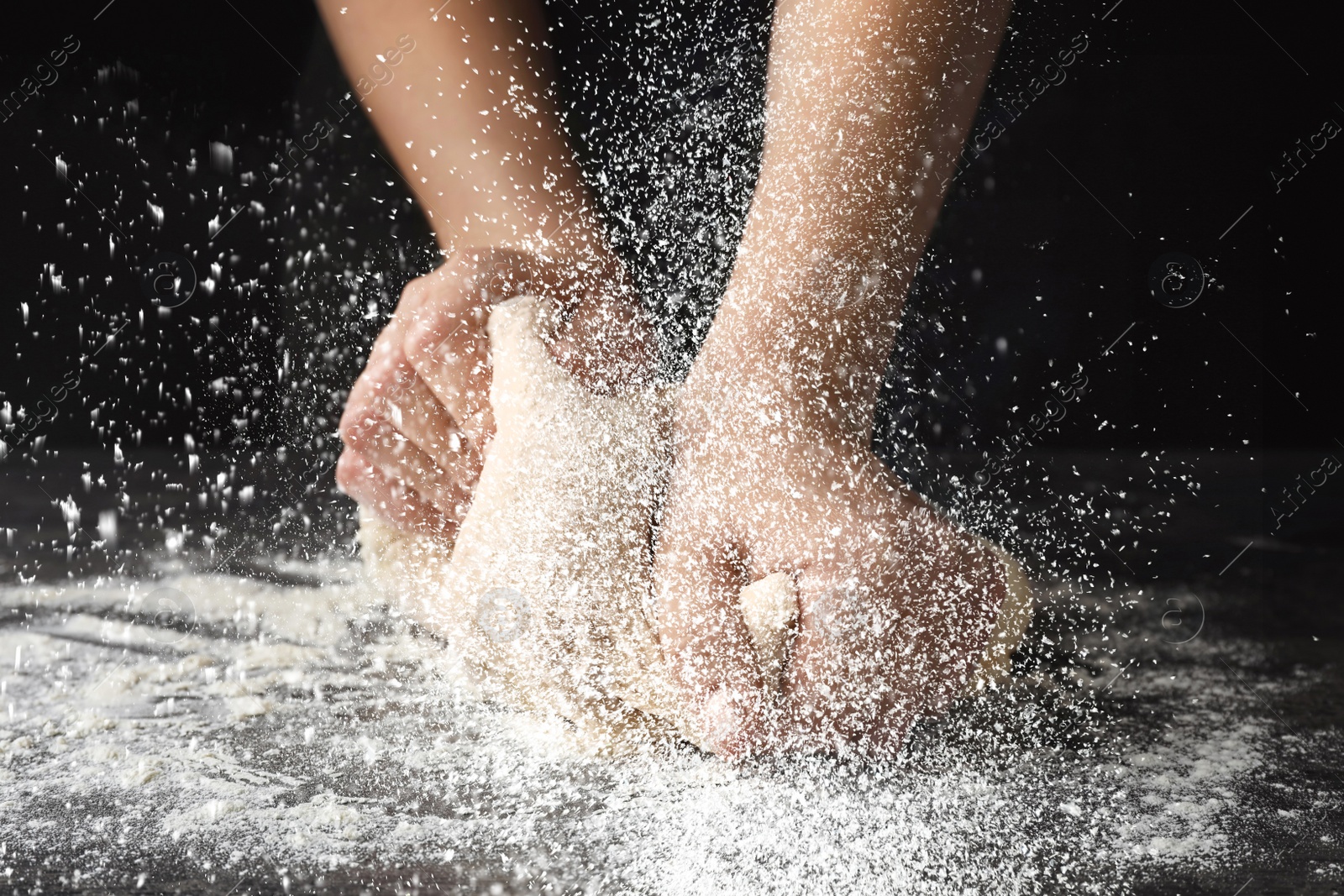 Image of Young woman kneading dough at table, closeup