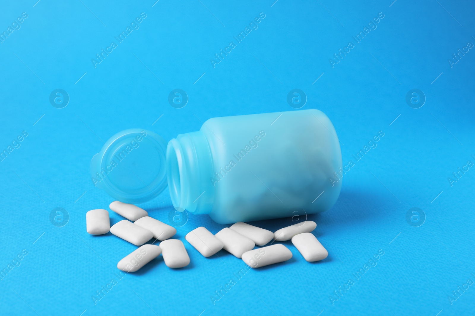 Photo of Jar with chewing gums on light blue background