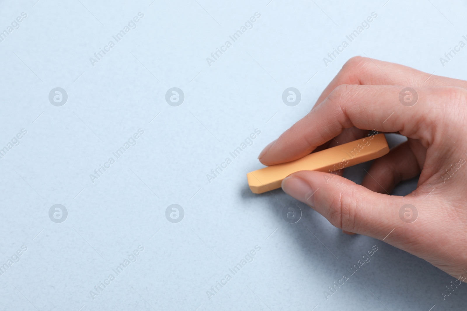 Photo of Woman drawing on light blue paper with pastel, closeup. Space for text