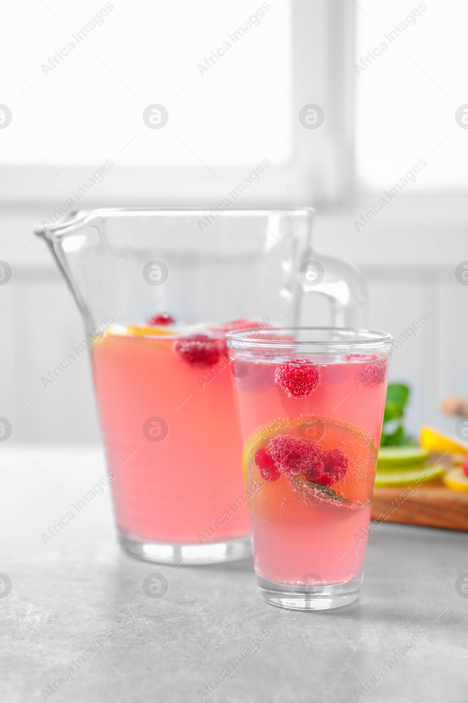 Photo of Jug and glass of fresh lemonade with berries on table