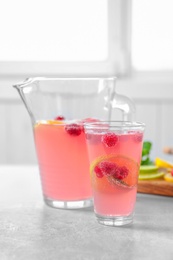 Jug and glass of fresh lemonade with berries on table