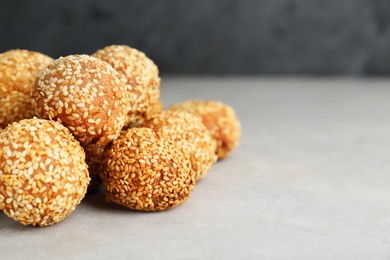 Photo of Delicious sesame balls on light grey table, closeup. Space for text