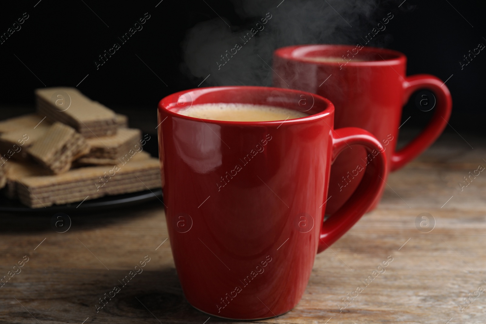 Photo of Delicious coffee and wafers on wooden table