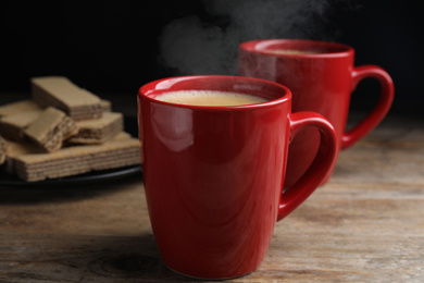 Photo of Delicious coffee and wafers on wooden table