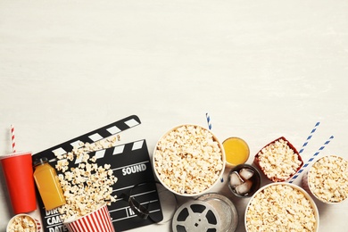 Flat lay composition with popcorn, cinema clapperboard and space for text on light background