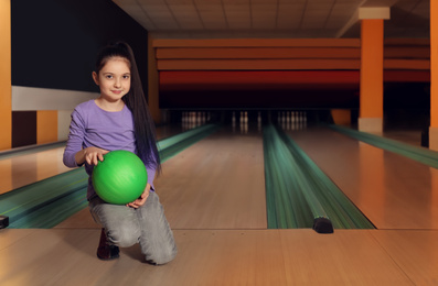 Photo of Little girl with ball in bowling club