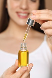 Woman with essential oil on brown background, selective focus