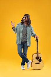 Photo of Stylish hippie man with guitar on orange background