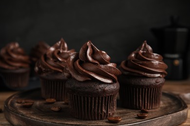 Photo of Delicious chocolate cupcakes with cream on wooden table