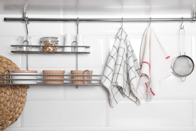 Photo of Different kitchen towels hanging on hook rod and shelves with ramekins indoors