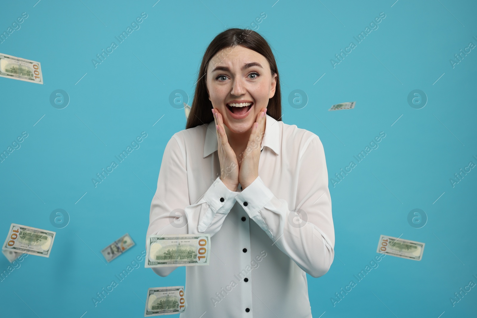 Photo of Excited woman under money shower on light blue background