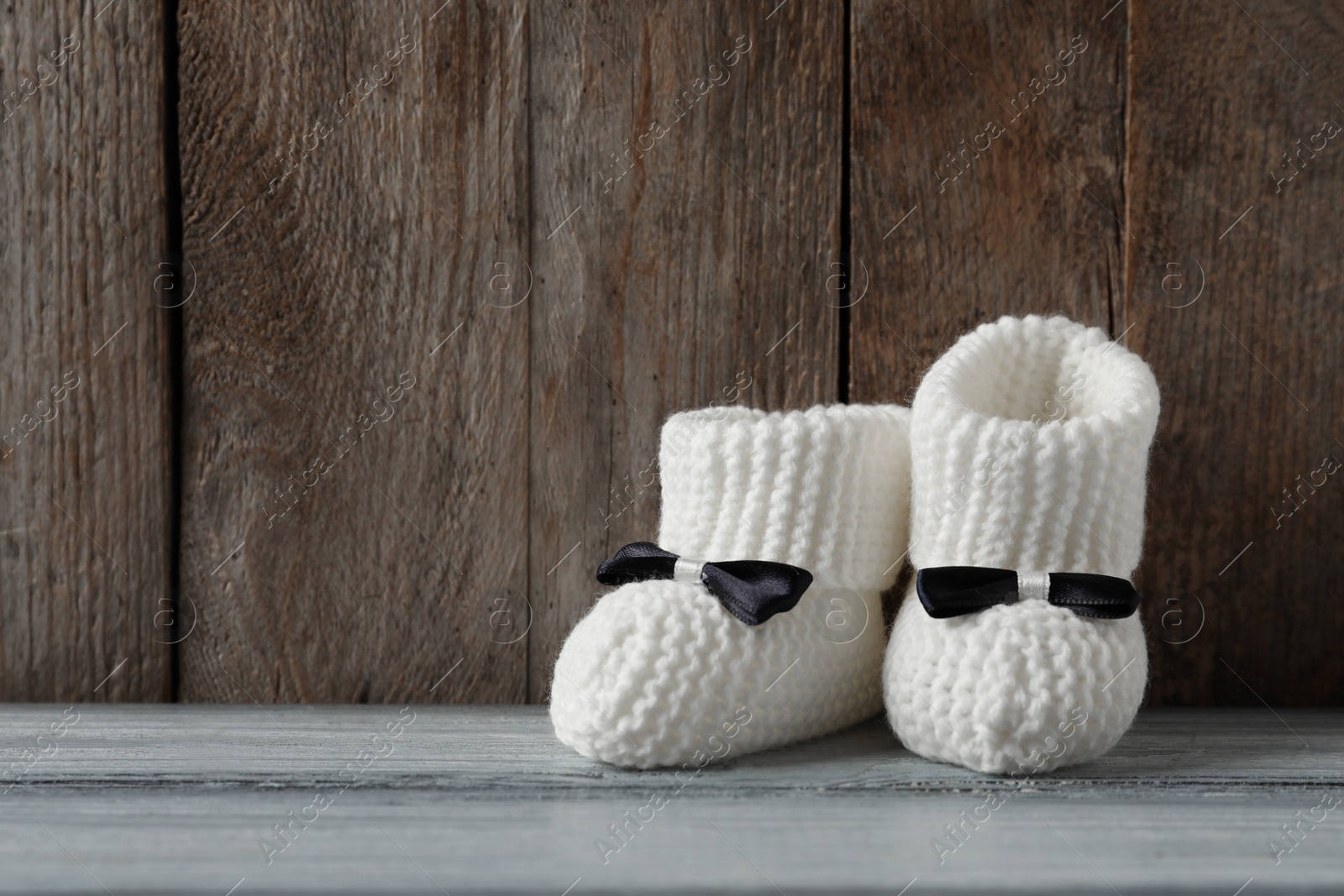 Photo of Handmade baby booties on table against wooden background. Space for text