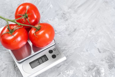 Photo of Kitchen scale with tomatoes on grey textured table. Space for text