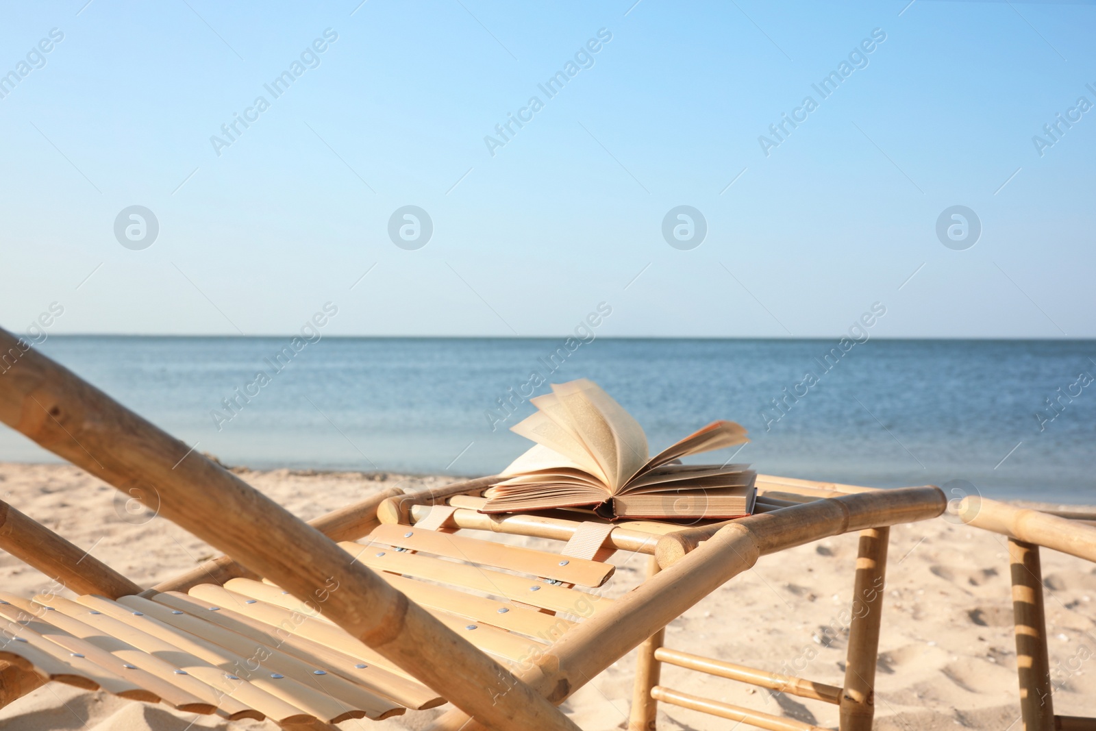 Photo of Book on wooden deck chair at seaside. Reading while vacation