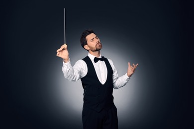 Photo of Professional conductor with baton on dark background