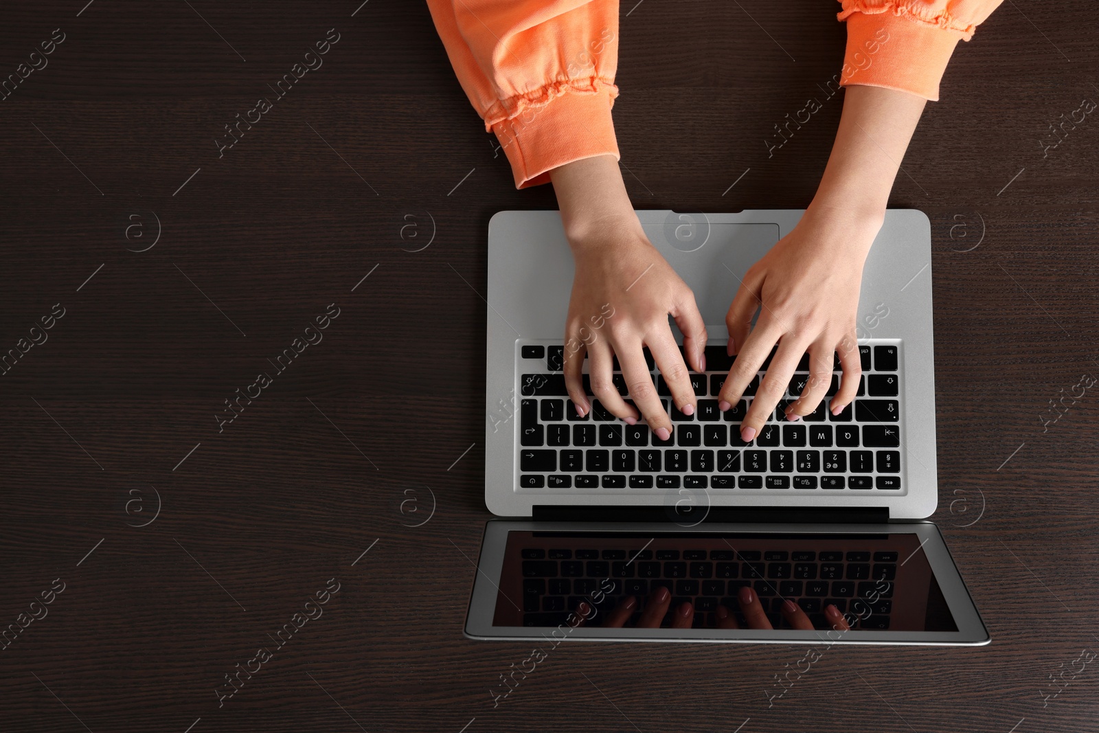 Photo of Woman working with laptop at wooden table, top view. Space for text