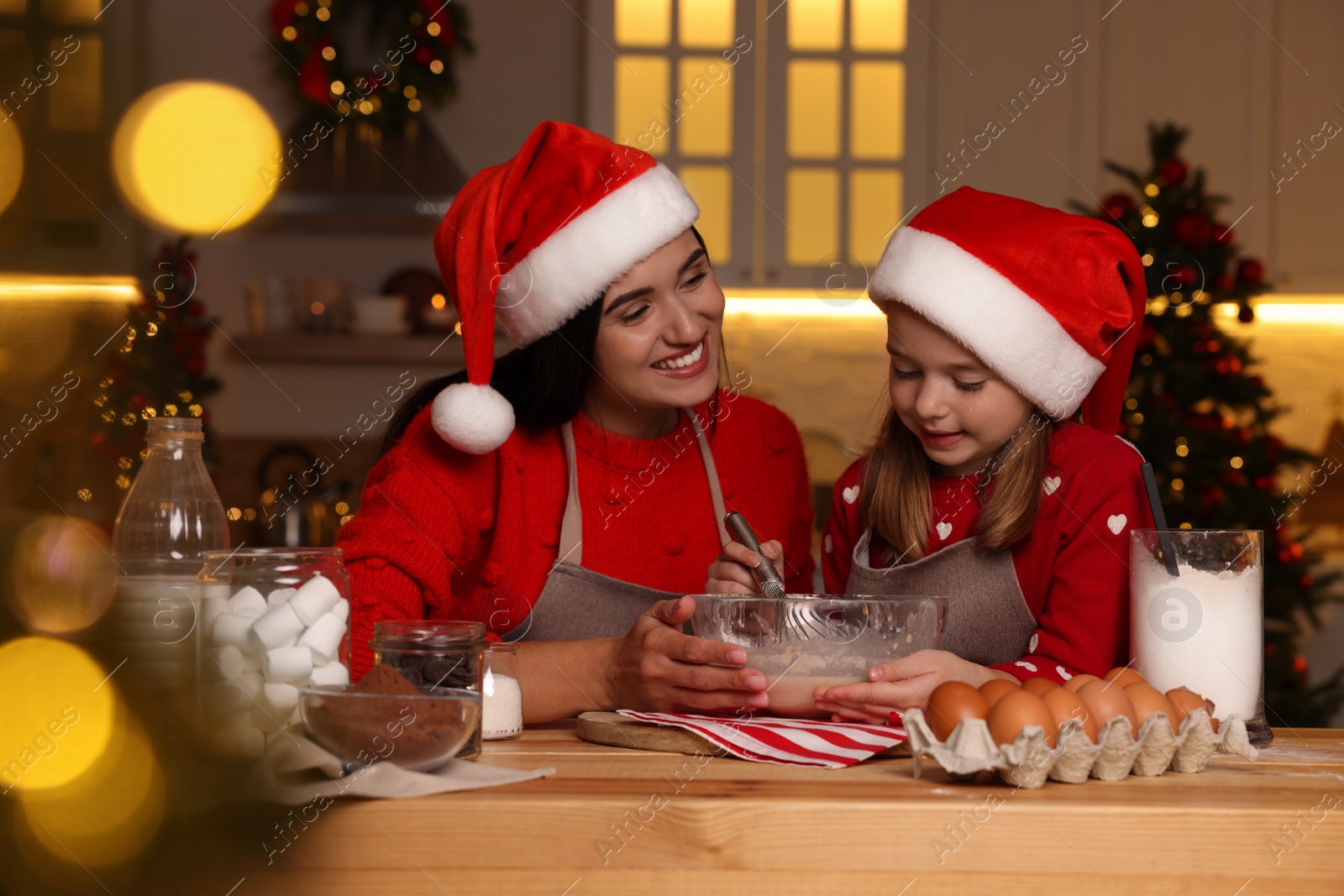 Photo of Happy mother and her daughter making dough for Christmas cookies at home