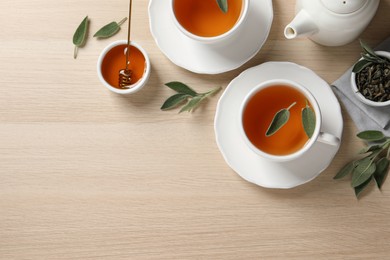 Photo of Flat lay composition with aromatic sage tea on wooden table. Space for text