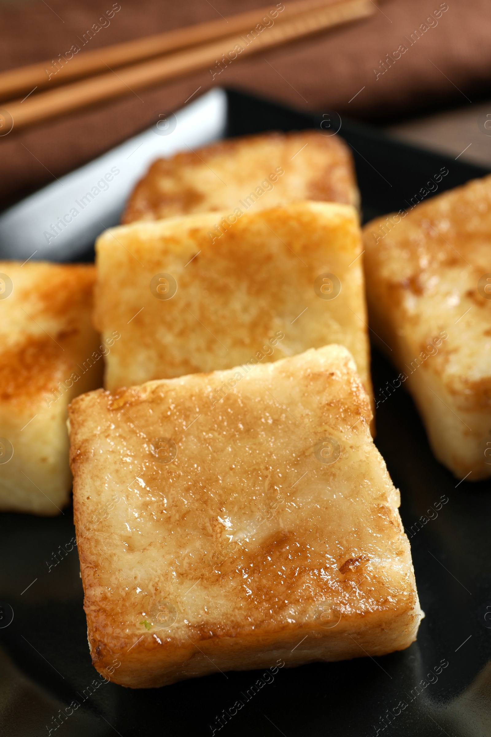 Photo of Delicious turnip cake on ceramic black plate, closeup