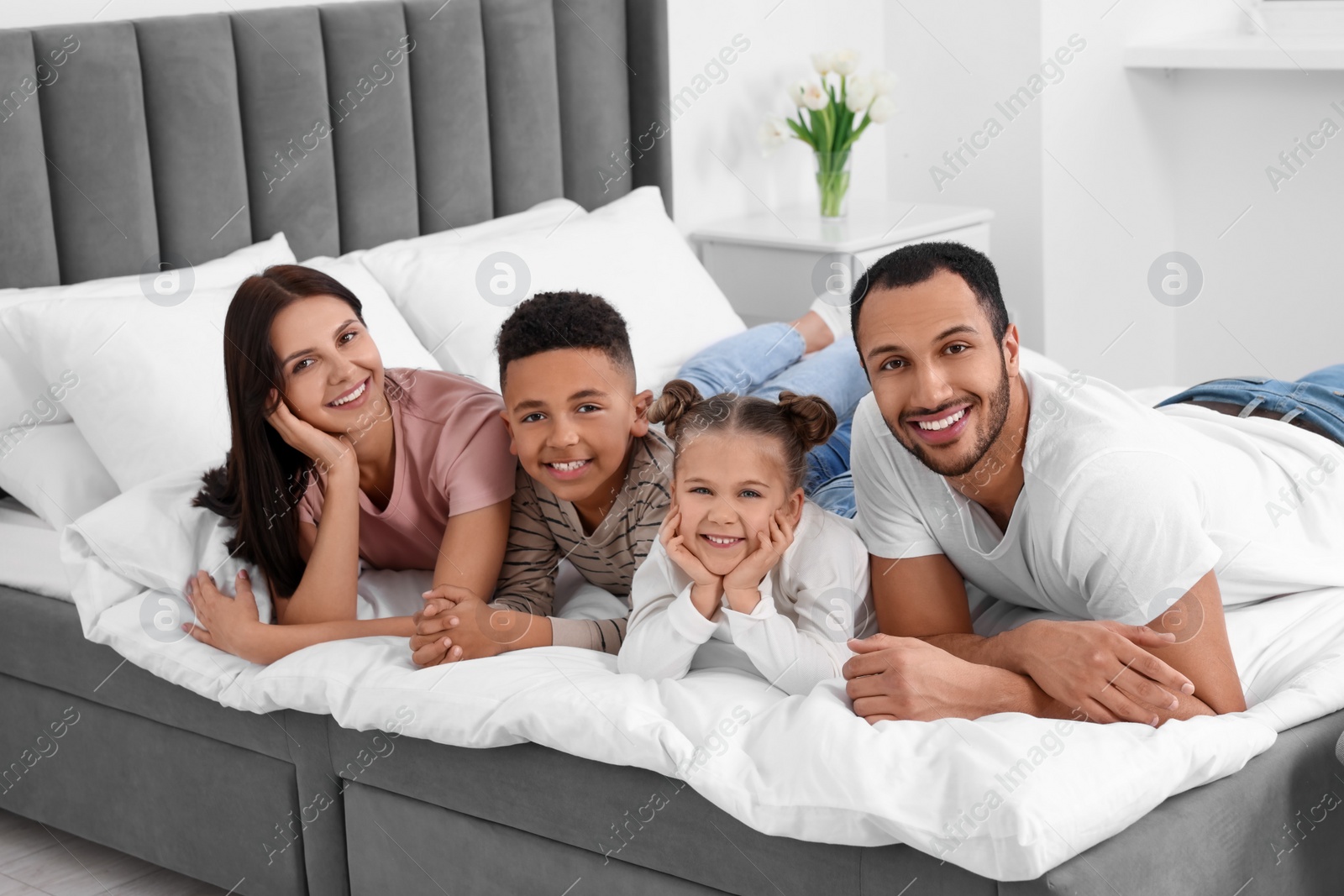 Photo of Happy international family lying on bed at home