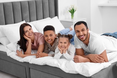 Photo of Happy international family lying on bed at home