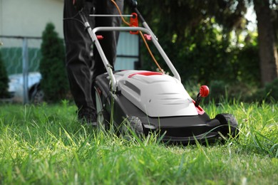 Photo of Man cutting grass with lawn mower in garden, closeup