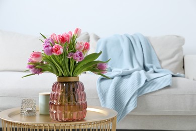 Photo of Beautiful bouquet of colorful tulip flowers on coffee table in room, space for text